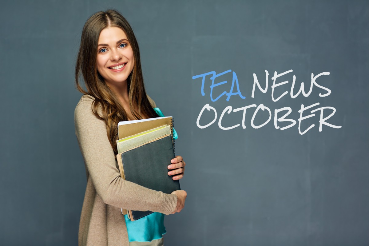 Female teacher carrying books in front of blackboard with TEA News October writing