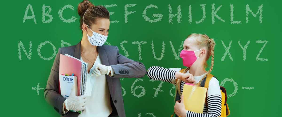 Woman teacher and schoolgirl wearing face-masks and touching elbows